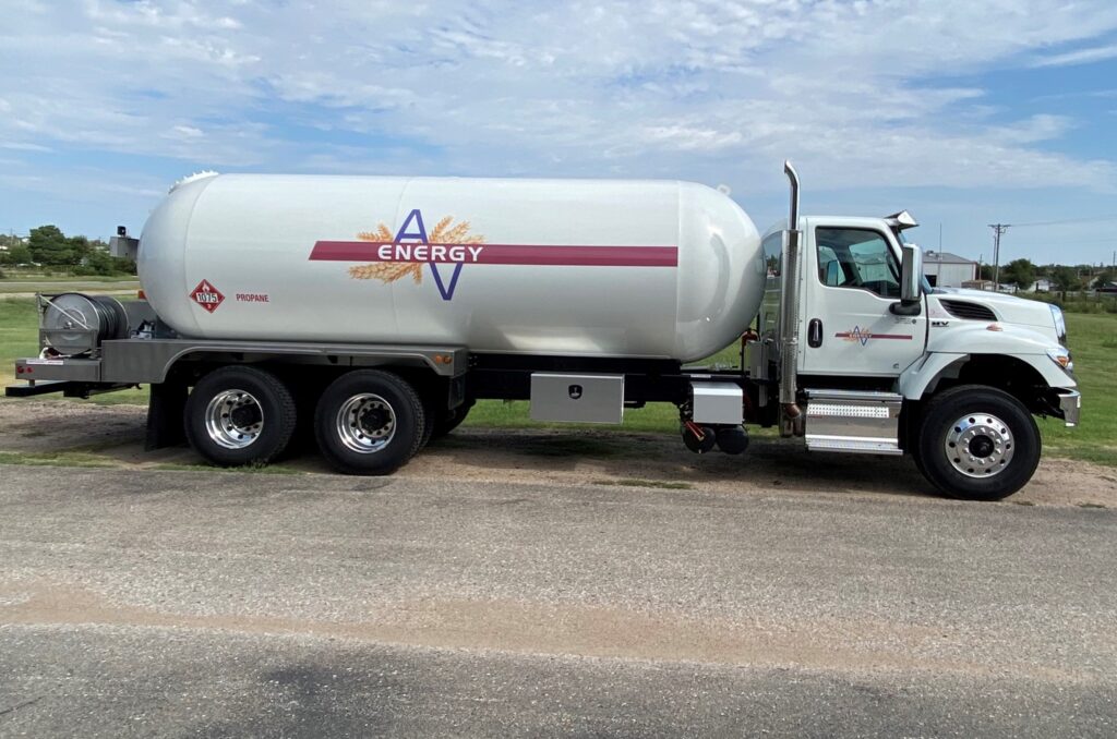 White propane delivery truck with Energy logo parked on pavement, grass and trees in the background.